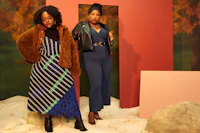 two women standing next to each other in front of a wall